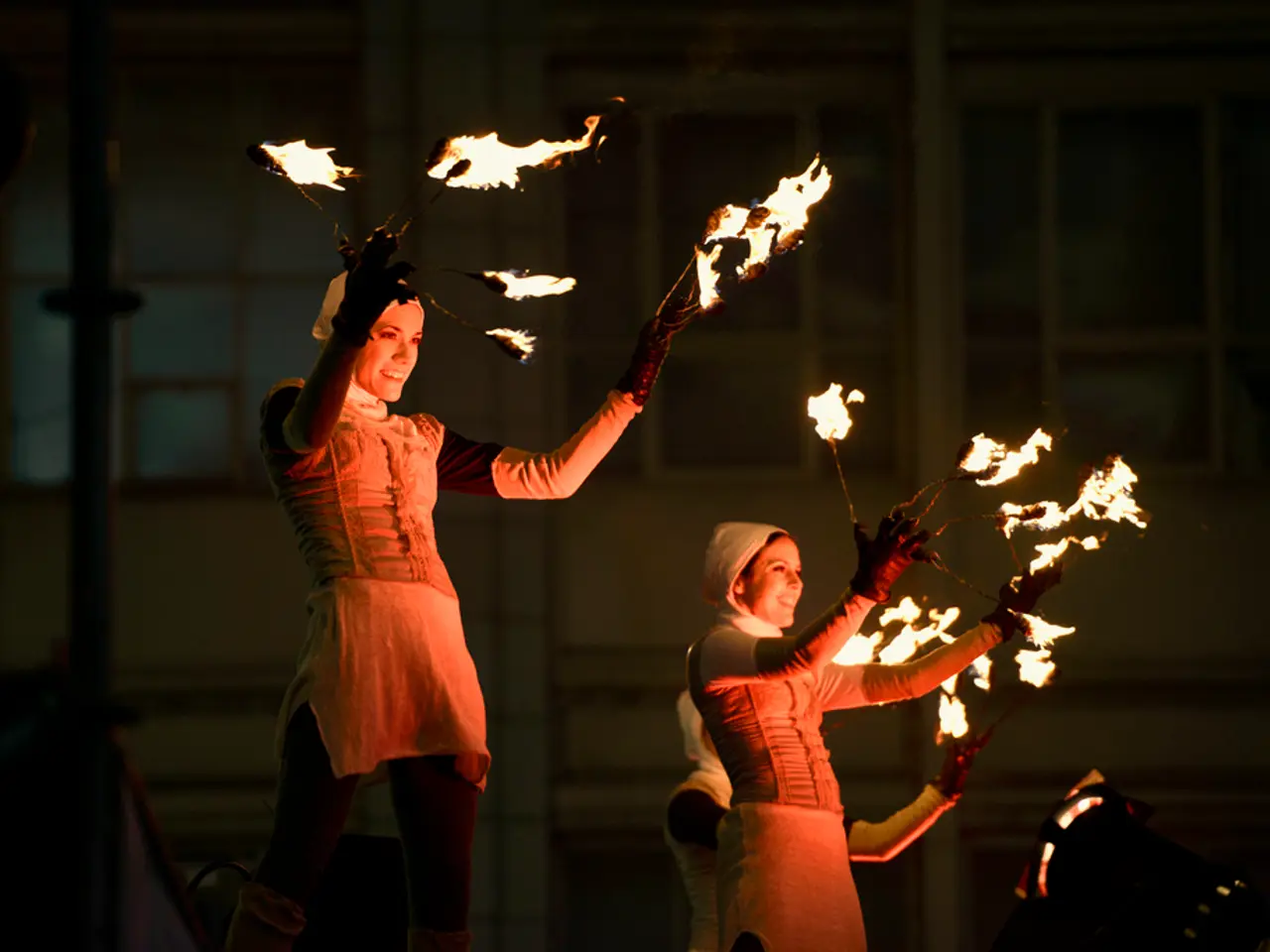 In the middle of the image few people are standing and holding some fire sticks. Behind them there...