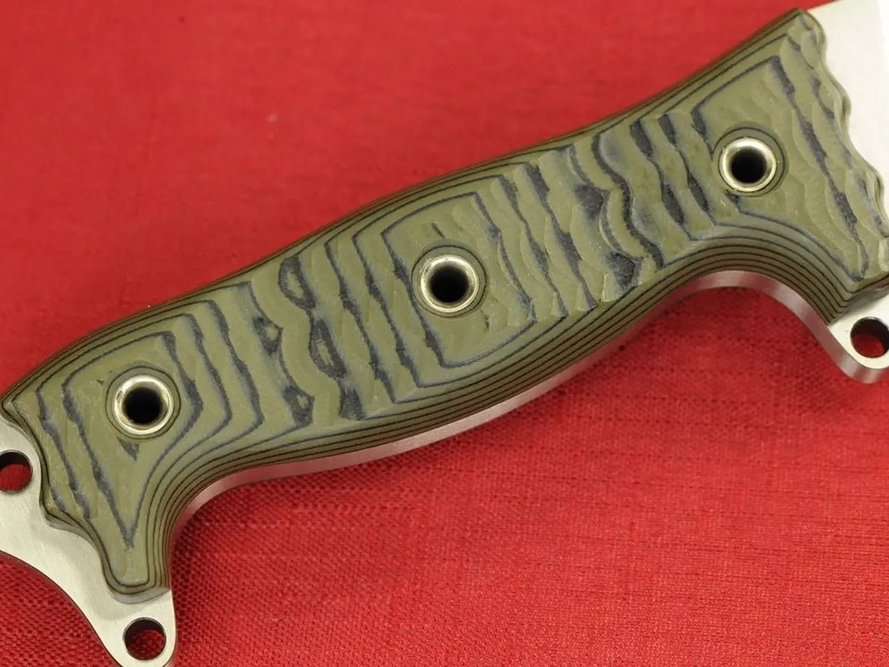 In this picture, we see a metal knife on the red color cloth.