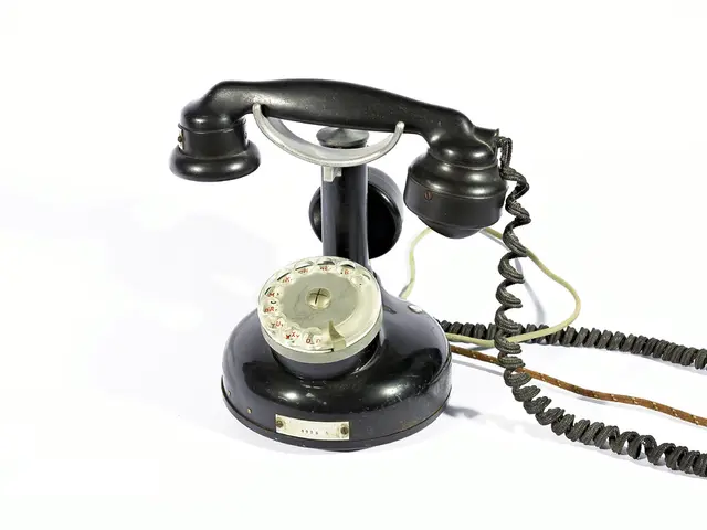 In this picture there is a black color telephone and there are numbers behind the glass and there...