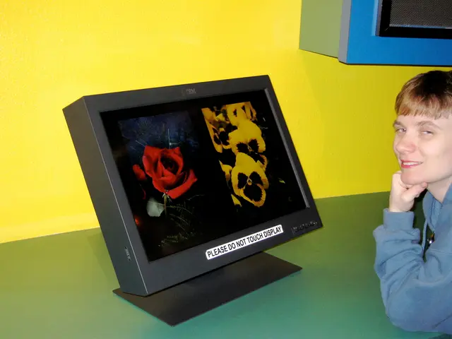 This image consists of a monitor in black color is kept on the desk. To the right, there is a man....