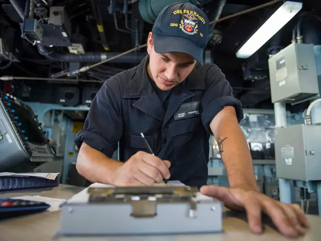 In this image I see a man who is holding a pen in his hand and I see that he is wearing a black...