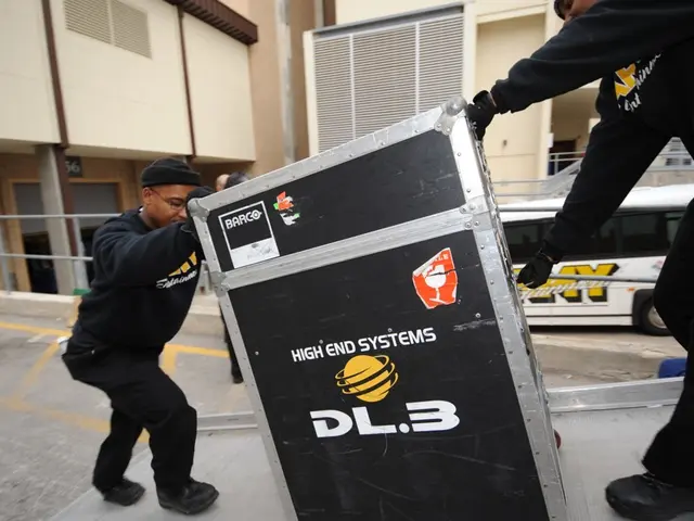 This picture shows buildings and we see a bus and couple of men holding a box and they wore black...