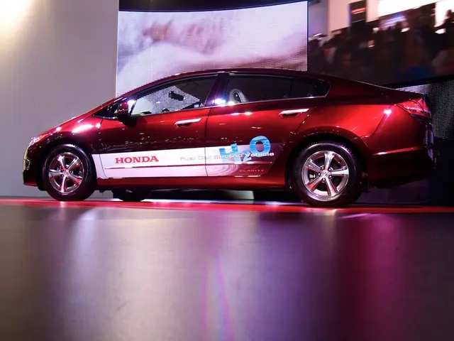 In this picture I can see a red car, and in the background there are screens.