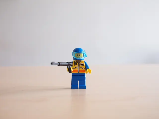 In this image there is a small toy which is holding the gun is on the table.
